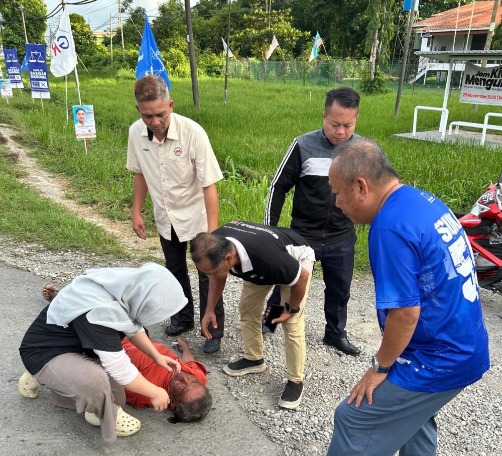 Dr Nurfazera Jafry (left) provides emergency treatment to a man, just released from hospital, who fell on a road while on his way home in Sukau, Sabah on November 26, 2025. — The Borneo Post pic