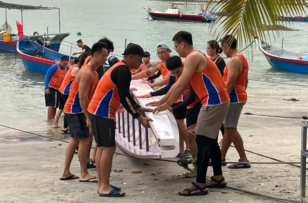 Penang Island Paddlez Club members carry a dragon boat in this undated photograph. — Penang Island Paddlez Club pic