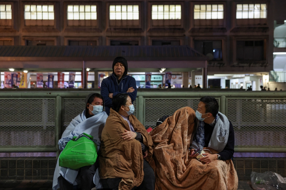 Evacuees wrapped in blankets rest on a nearby platform after a major fire at Wang Fuk Court housing estate, in Tai Po, Hong Kong November 26, 2025. — Reuters pic  