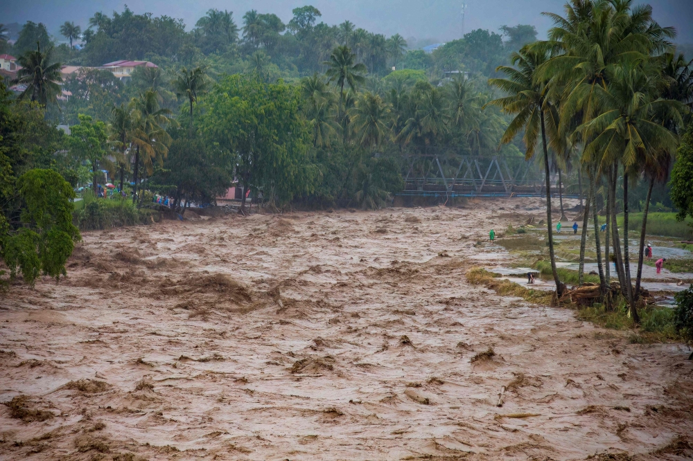 People stay on the riverbanks during flooding in Padang, West Sumatra province on November 27, 2025. — AFP pic 