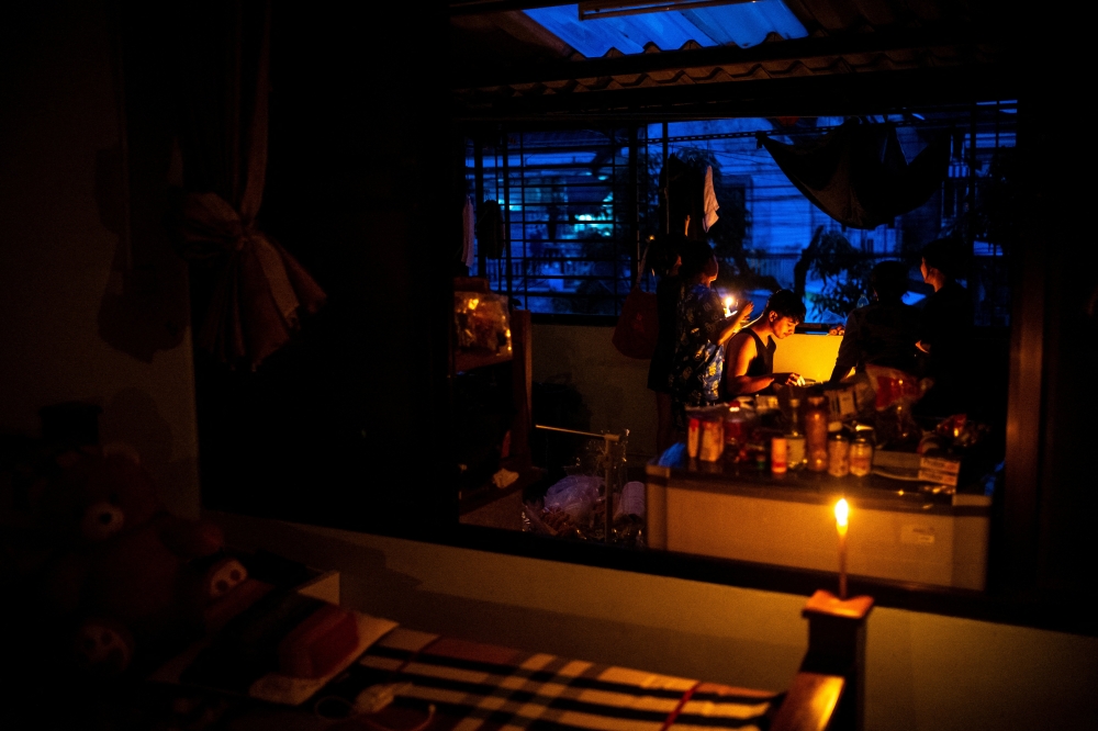 Amphorn Kaeophengkro, 44, Jaswee Pathan, 24, and Rathanawadee Wangsirivej, 22, have dinner by candlelight on the balcony of a flooded house, following power outages caused by deadly flooding in Hat Yai district, Songkhla province, Thailand, November 28, 2025. — Reuters pic
