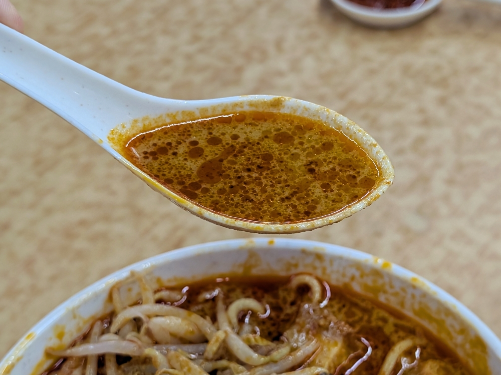 咖喱呈浓稠的橙色，上面覆盖着一层火红的油。 — 图片由刘启生拍摄