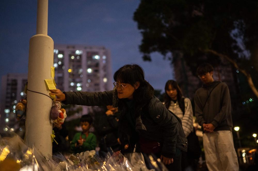 A woman sticks a post-it note outside the Wang Fuk Court in the aftermath of the deadly November 26 fire in Hong Kong's Tai Po district on November 29, 2025. An outpouring of grief was set to sweep Hong Kong on November 29 as an official, three-day mourning period began with a moment of silence for the 128 people killed in one of the city's deadliest fires. — AFP pic