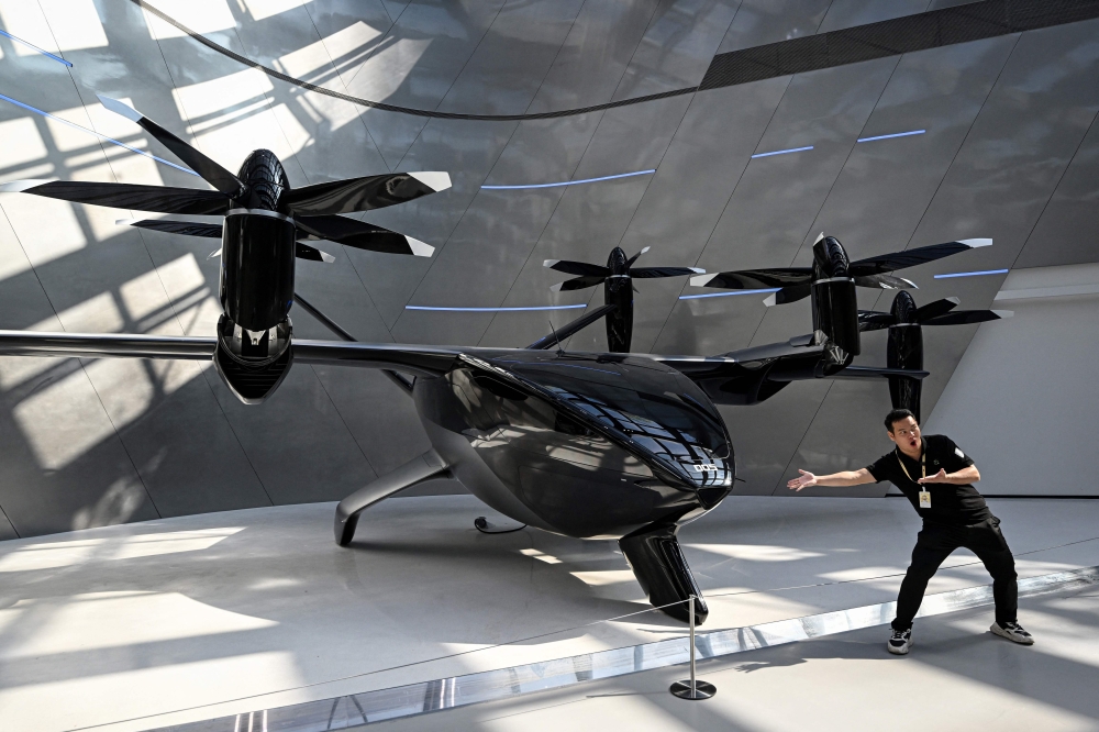 A journalist poses next to Xpeng’s latest A868 flying car during a showroom tour in Guangzhou. — AFP pic