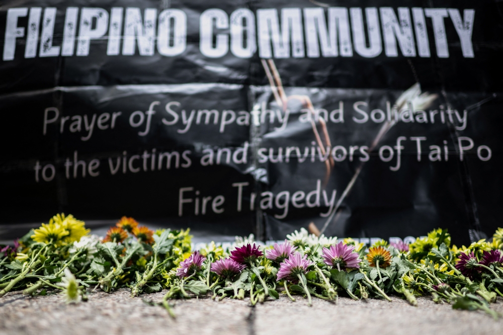 Flowers are placed for victims of the deadly November 26 fire as Philippine nationals in Hong Kong take part in a community prayer service at Tai Po. — AFP pic
