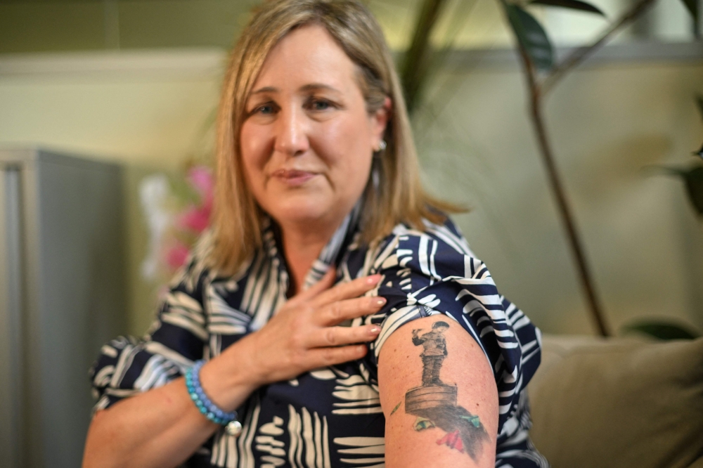 Mia Bannister, mother of the late 14-year-old Ollie Hughes, shows a tattoo dedicated to her son during an interview in Sydney. — AFP pic