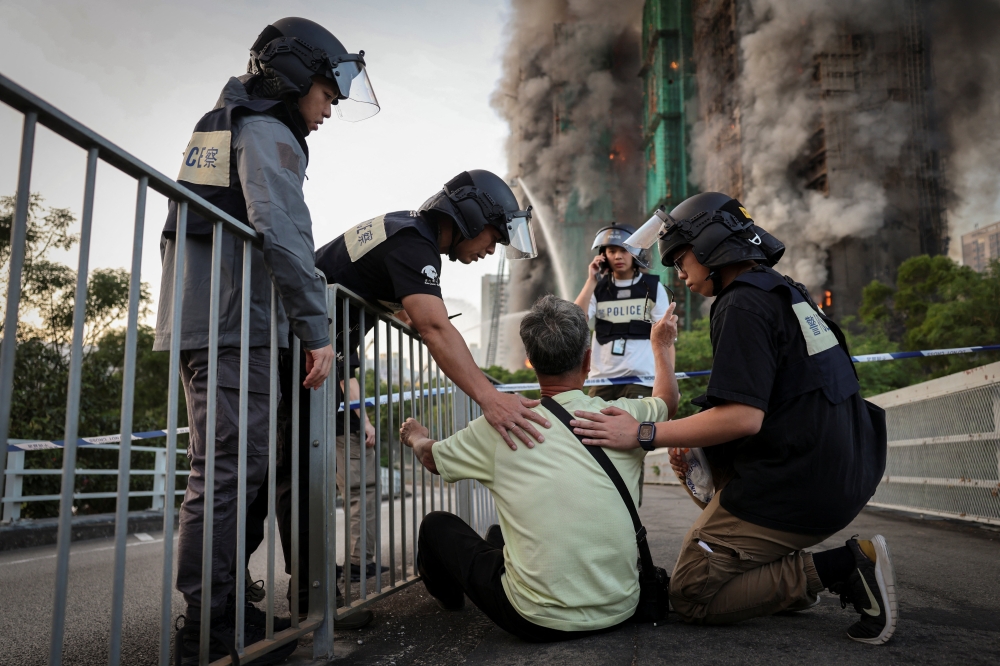 Police officers calm Wong, a 71-year-old man who claims his wife is trapped inside Wang Fuk Court housing complex during a major fire, in Tai Po, Hong Kong, November 26, 2025. — Reuters pic