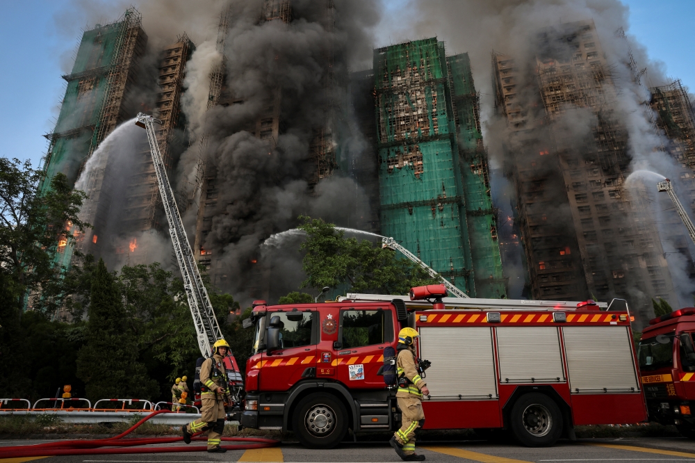 Firefighters walk near the site of a major fire at Wang Fuk Court housing complex, during a deadly fire, in Tai Po, Hong Kong, November 26, 2025. — Reuters pic
