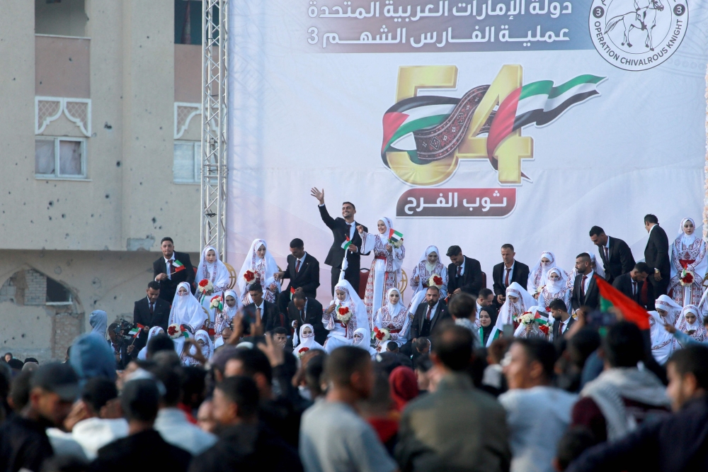 Some of the 54 brides and grooms gather on a stage during a mass wedding in Khan Yunis, southern Gaza Strip on December 2, 2025. ‘The Dress of Joy’, is a project helping 54 grooms in the the Gaza Strip to get married, an initiative that coincided with United Arab Emirates’ (UAE) 54th National Day. — AFP pic 