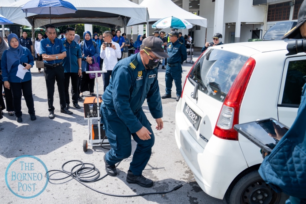 Wan Abdul Latiff (2nd left) and other DoE officials observe a vehicle emissions test. — The Borneo Post pic