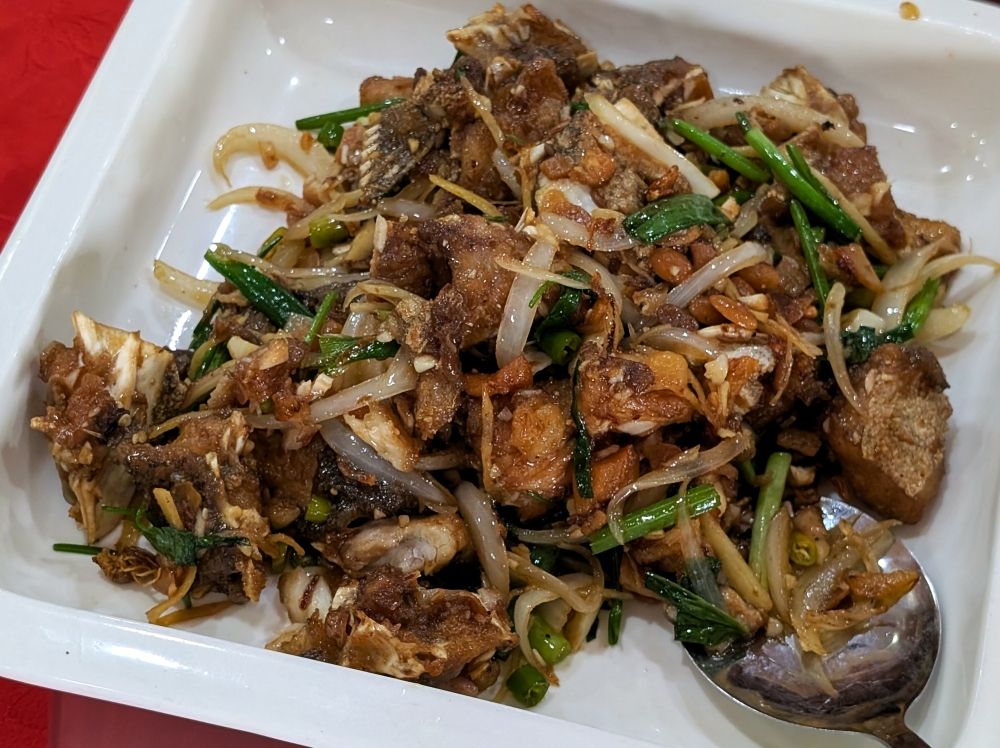 The stir-fried fish head is covered in a shower of crispy lard. — Picture by Ethan Lau