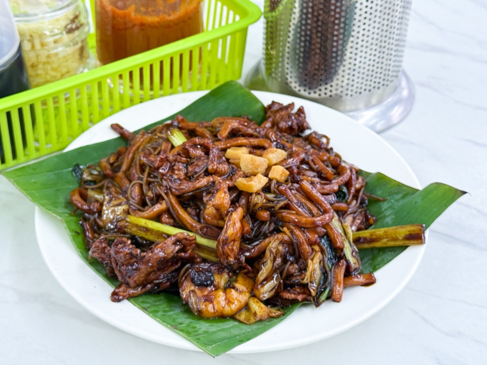 Hokkien Mee is a signature here with the smooth noodles glistening in an ebony black sauce and topped with fried lard fritters . — Picture by Lee Khang Yi