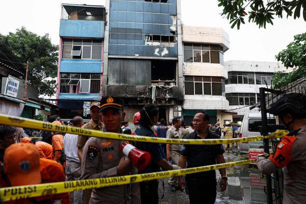 Police officers stand near a seven-storey building damaged by fire, in Jakarta December 9, 2025. — Reuters pic  