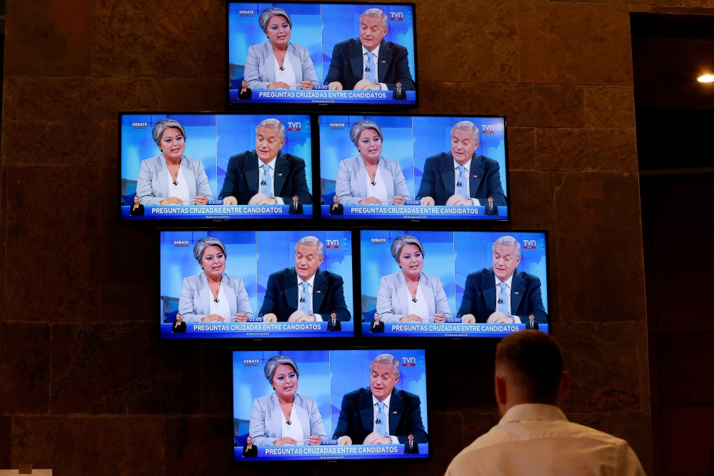 A journalist watches the debate between Chile's presidential candidates Jose Antonio Kast of the Partido Republicano party and Jeannette Jara, of the Unidad por Chile coalition, at the National Television Association headquarters in Santiago, on December 9, 2025. — AFP pic