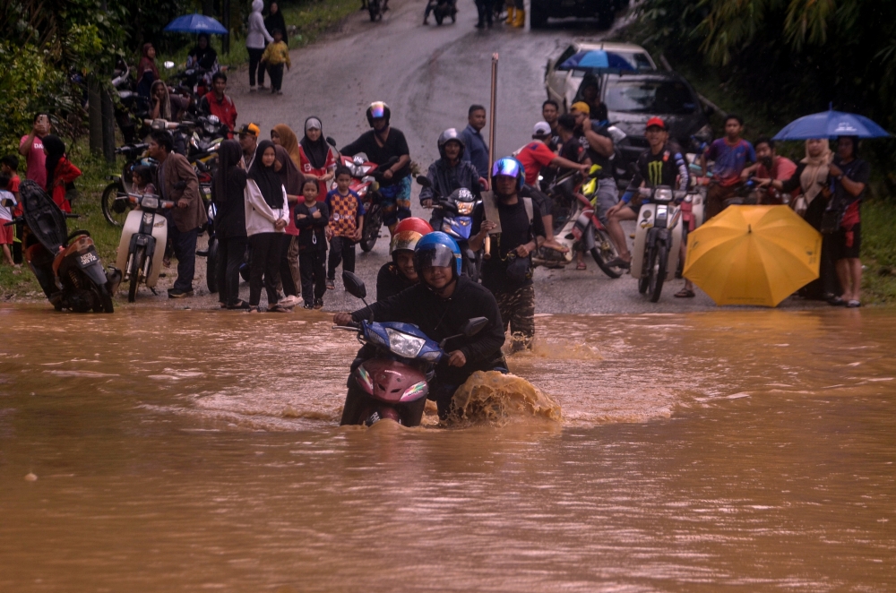 File picture of Orang Asli residents of the Temiar tribe walking along the path flooded by Sungai Betis due to heavy rain in Gua Musang, December 25, 2023. Residents in the district of Gua Musang in Kelantan, especially those living in low-lying areas, have been warned of the potential for a second wave of flooding at any time. — Bernama pic