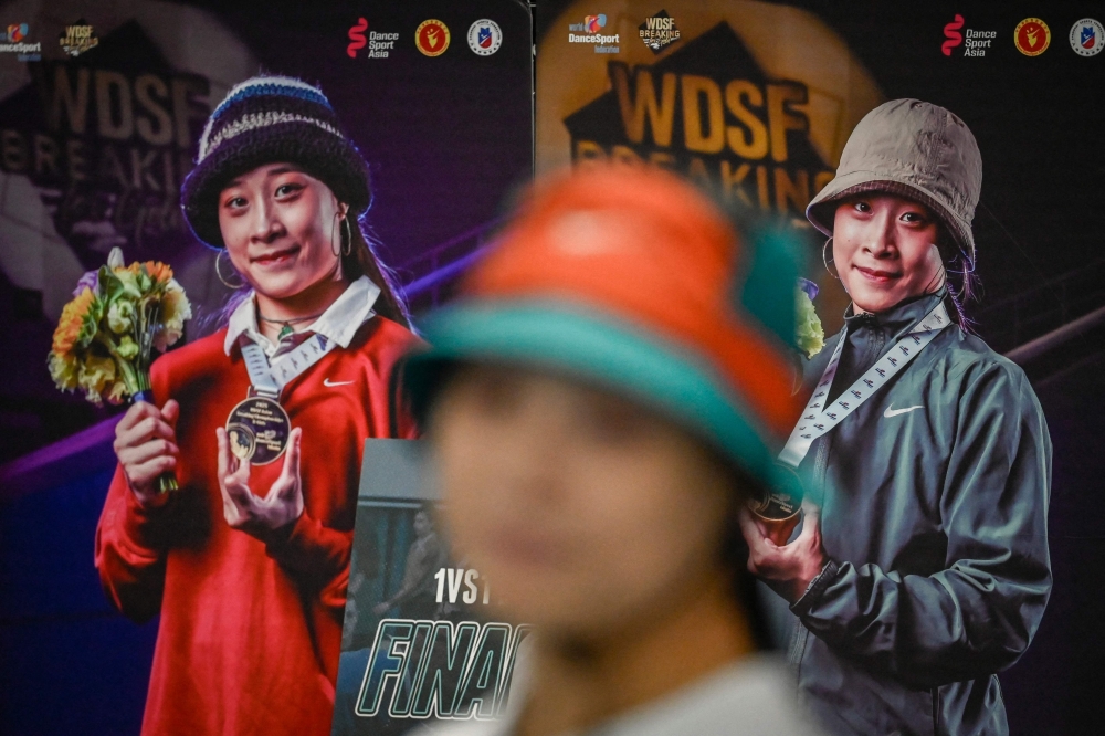 This picture taken on November 25, 2025 shows Guo Pu standing in front of a poster showing her winning awards at a breakdancing studio in Pingyi county, in eastern China's Shandong province. — AFP pic