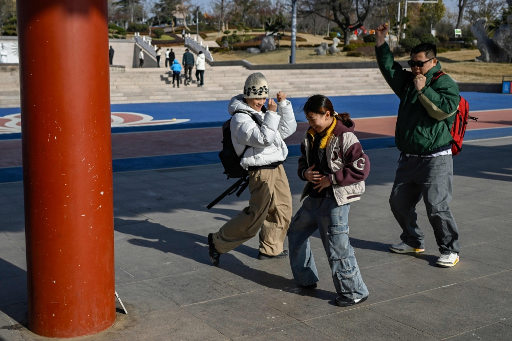 This picture taken on November 26, 2025 shows Guo Pu (left) dancing with her coach Li Shilong (right) and teammate Deng Siqi (centre) for a Douyin (TikTok) video at a park in Pingyi county, in eastern China's Shandong province. — AFP pic 