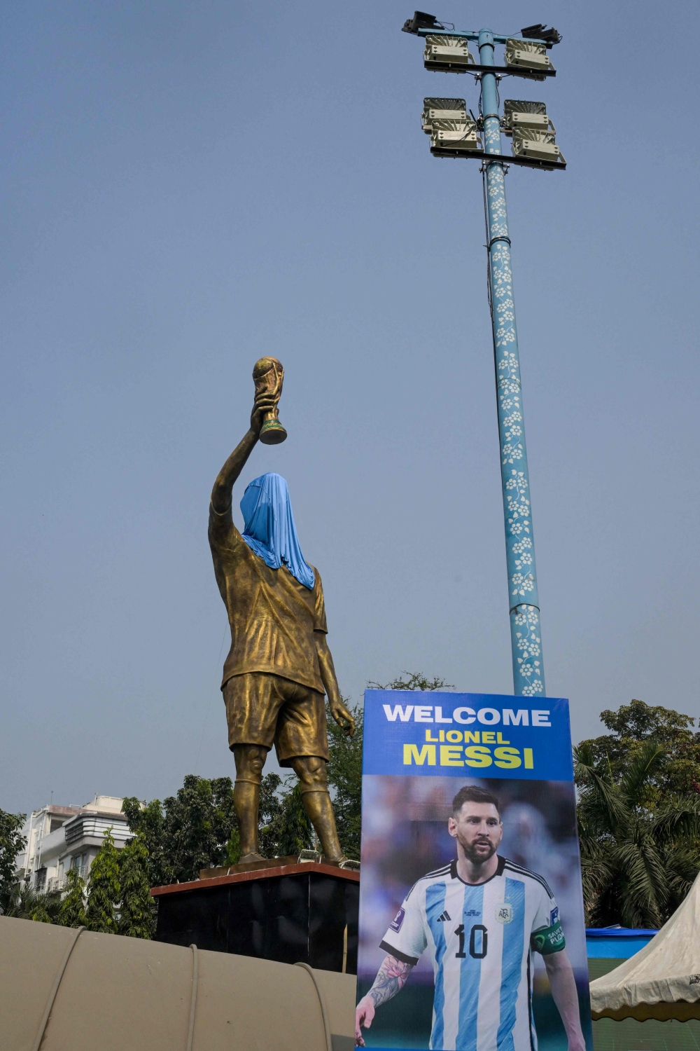 A poster of Lionel Messi is seen beside his veiled statue, on the eve of his visit, in Kolkata December 12, 2025. — AFP pic