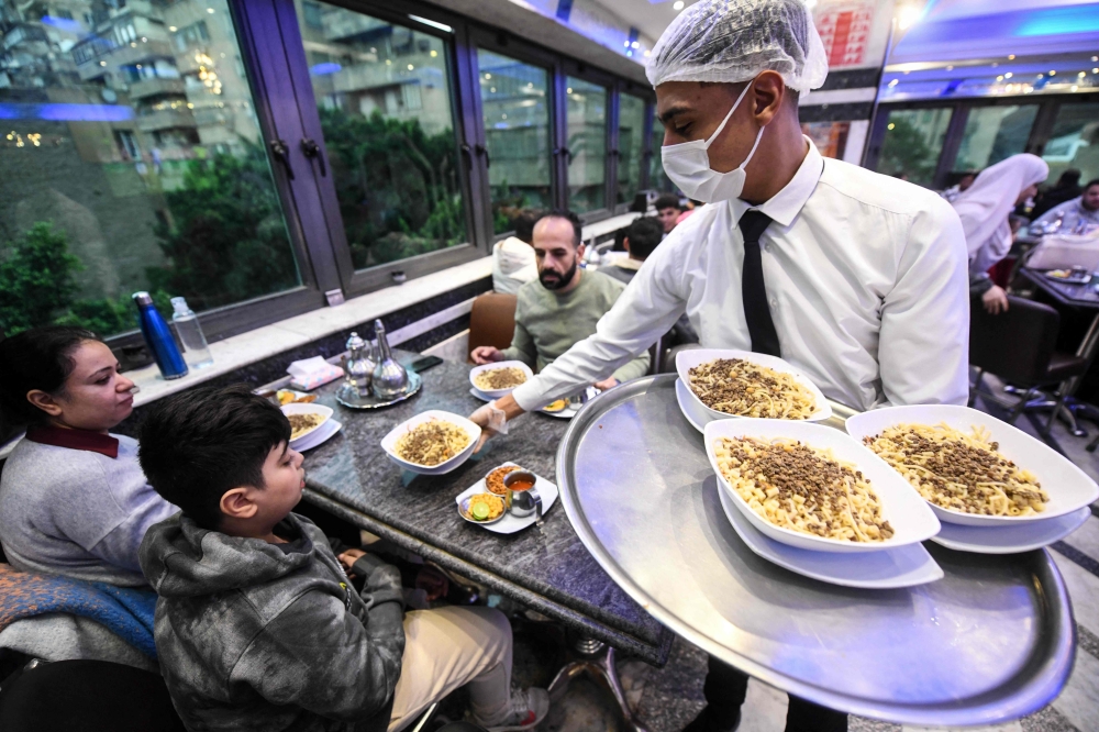 An Egyptian waiter serves koshary at Abou Tarek restaurant downtown Cairo as Unesco recognised the dish as an intangible cultural heritage on December 10, 2025. — AFP pic