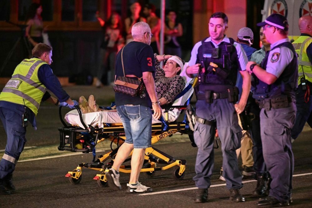 Health workers move a woman on a stretcher to an ambulance after a shooting incident at Bondi Beach in Sydney. — AFP pic