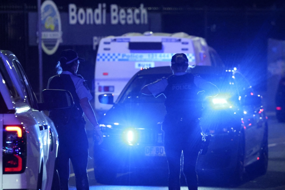 Police walk on a street after a shooting incident at Bondi Beach in Sydney earlier today. — AFP pic