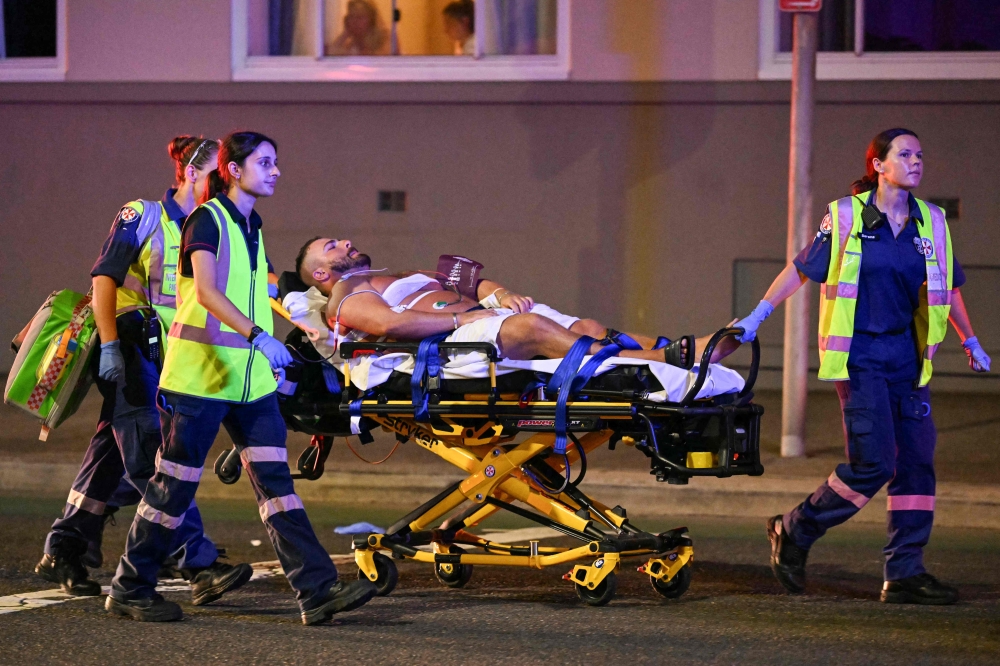 Health workers wheel a wounded man to an ambulance after a shooting at Sydney’s Bondi Beach on December 14, 2025. — AFP pic