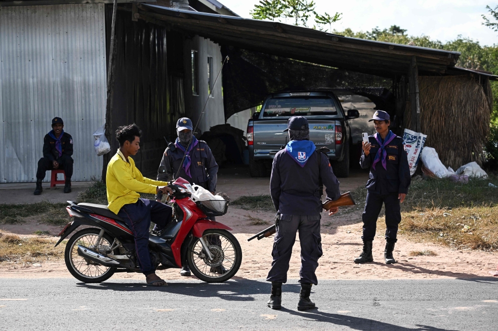 Security volunteers check the identification of a motorist as they remain in the evacuation zone to protect villagers’ homes and livestock during the conflict in the Thai province of Buriram, 10km from the border with Cambodia on December 13, 2025. — AFP pic