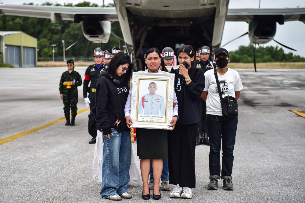 The mother and relatives of Special Forces volunteer Mustakim Majehma, who died in Cambodia–Thailand border clashes, carry his portrait during a military ceremony at Narathiwat airport, Thailand, on December 14, 2025. — AFP pic