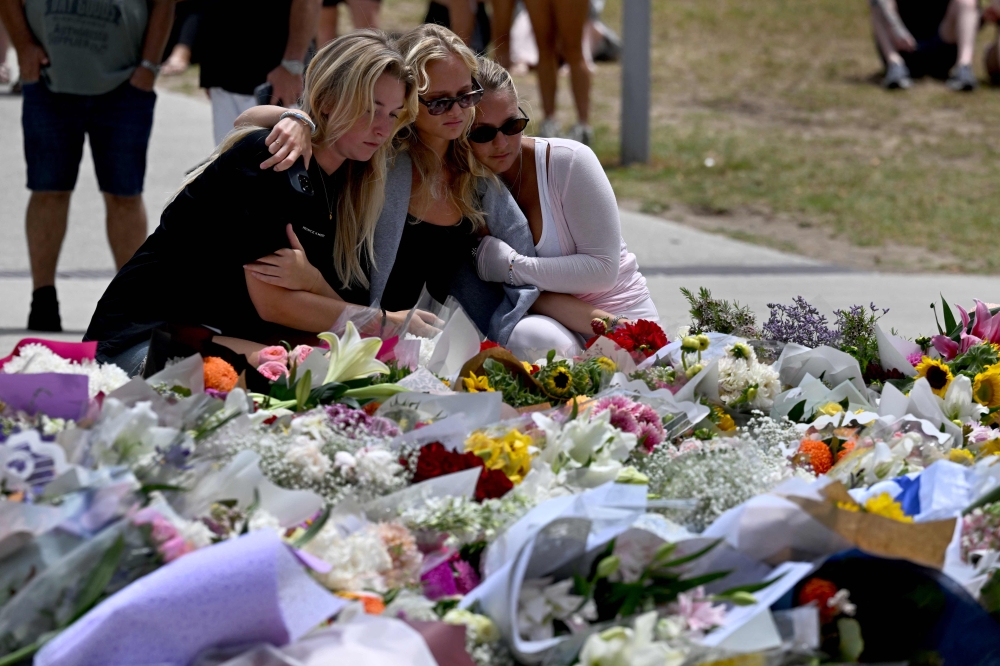 Mourners gather by floral tributes at the Bondi Pavillion in memory of the victims of a shooting at Bondi Beach, in Sydney on December 15, 2025. — AFP pic