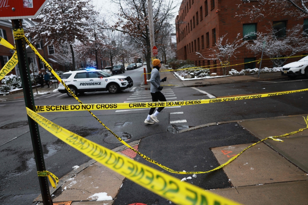 A person jogs by police tape near the campus at Brown University a day after a mass shooting that left at least two people dead and nine others injured on December 14, 2025 in Providence, Rhode Island. — Getty Images pic via AFP