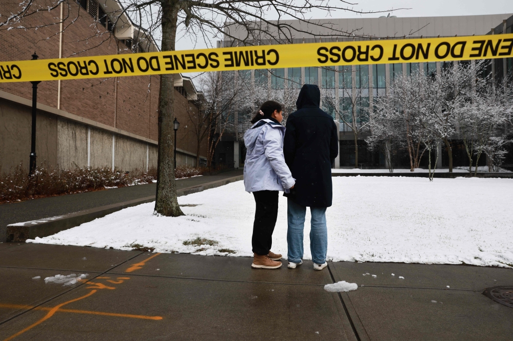 People pause outside of the engineering and physics building at Brown University, the site of a mass shooting that left at least two people dead and nine others injured, on December 14, 2025 in Providence, Rhode Island. — Getty Images pic via AFP