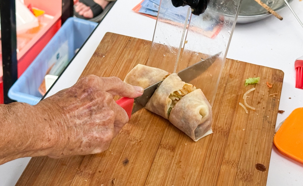 A nifty tool is used to guide the cutting of the 'popiah' into even pieces.