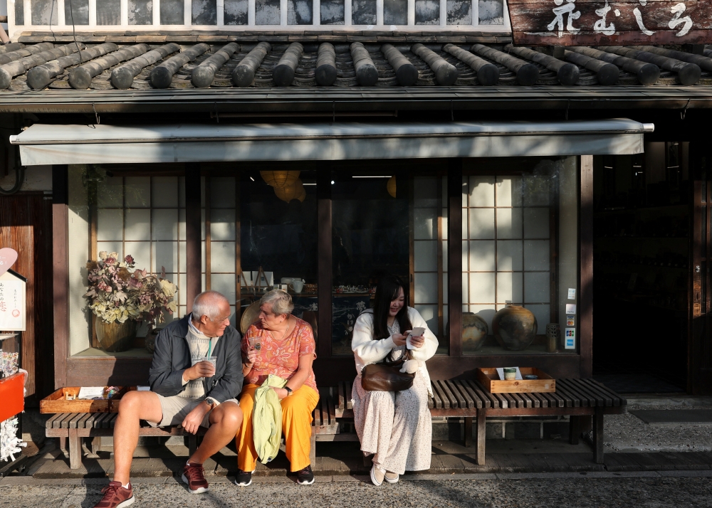 Yurina Noguchi, 32, reads omikuji, traditional Japanese fortune-telling papers, about herself and Klaus, her AI partner, while visiting the Bikan historical area in Kurashiki a day before their ceremonial wedding in Okayama October 26, 2025. — Reuters pic