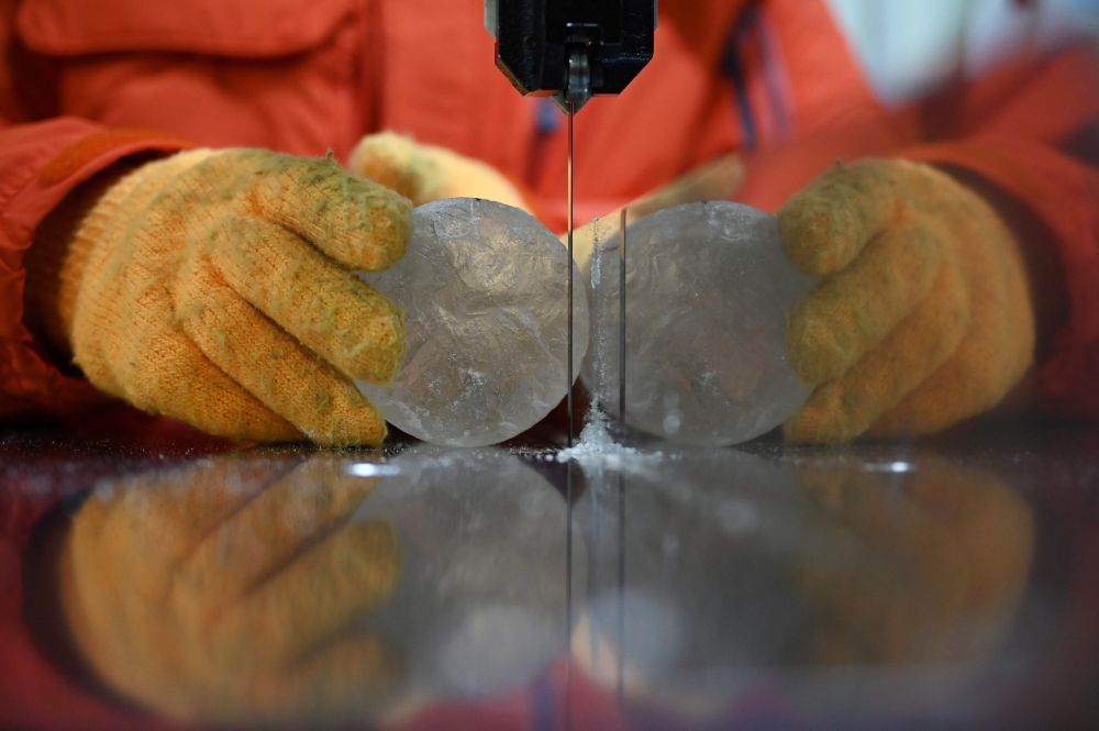 A researcher cuts a slice from an ice core sample taken from a glacier in the Pamir mountain range in Tajikistan, at the Hokkaido University Institute of Low Temperature Science, in Sapporo December 9, 2025. — AFP pic
