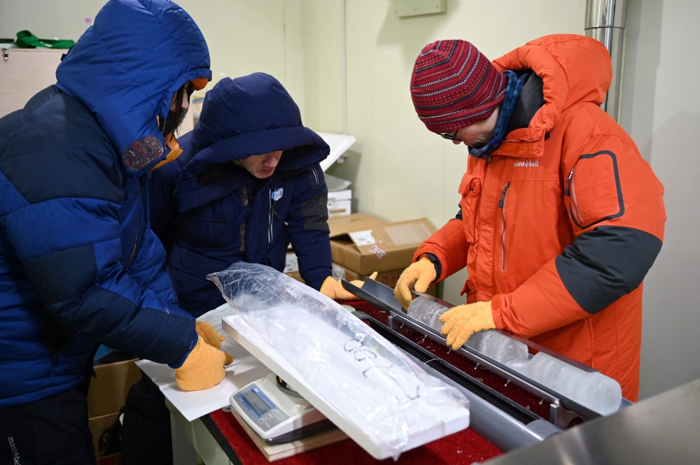 Researchers examine an ice core sample taken from a glacier in the Pamir mountain range in Tajikistan, at the Hokkaido University Institute of Low Temperature Science, in Sapporo December 9, 2025. — AFP pic