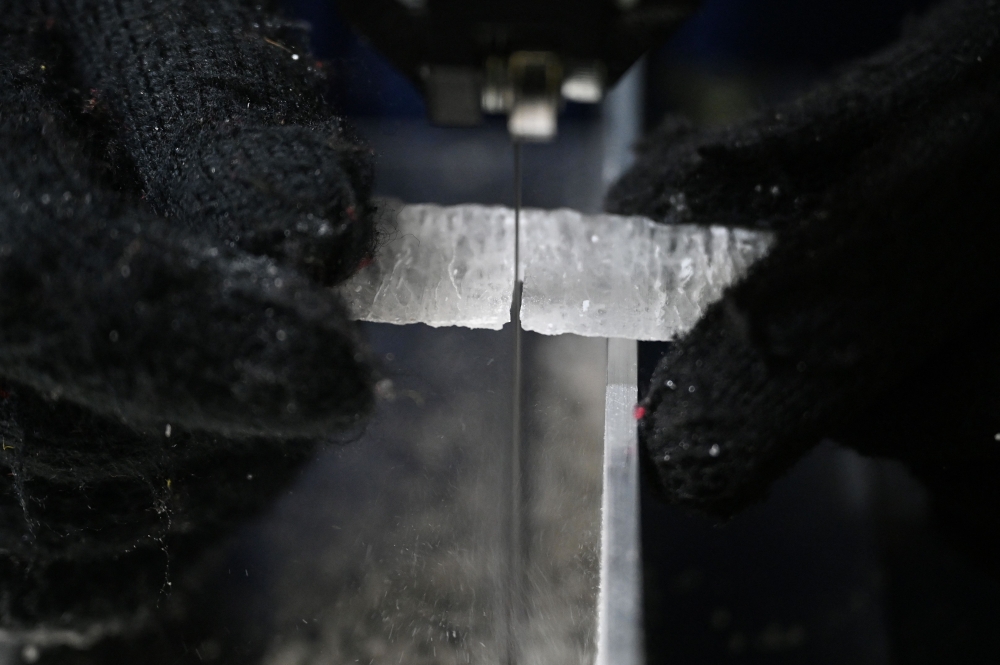 A researcher cuts a slice from an ice core sample taken from a glacier in the Pamir mountain range in Tajikistan, at the Hokkaido University Institute of Low Temperature Science, in Sapporo December 9, 2025. — AFP pic