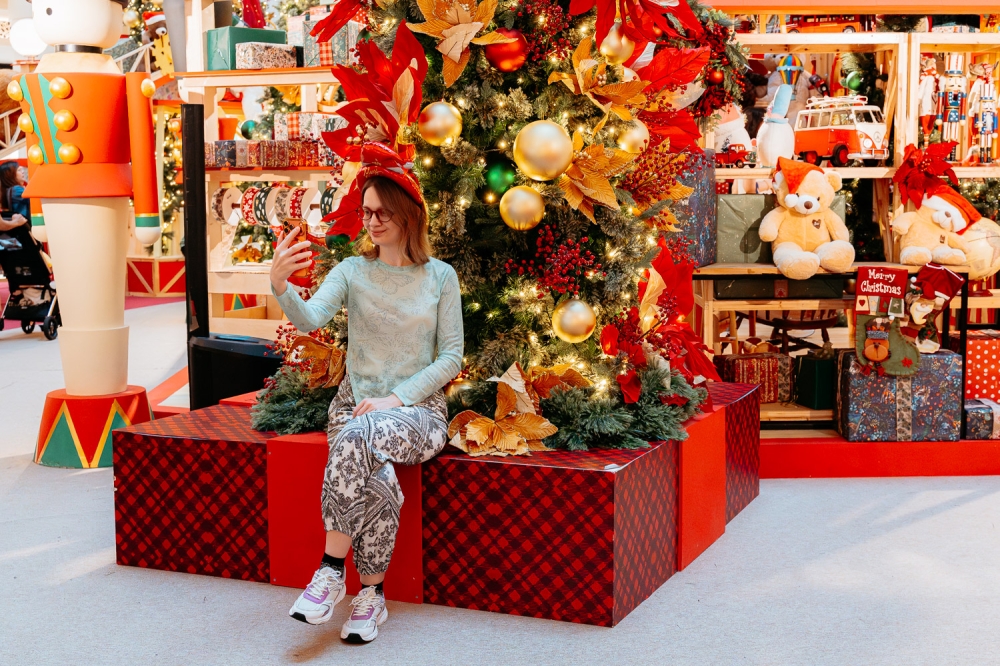 A shopper smiles for a selfie in front of the Christmas tree. — Picture by Raymond Manuel