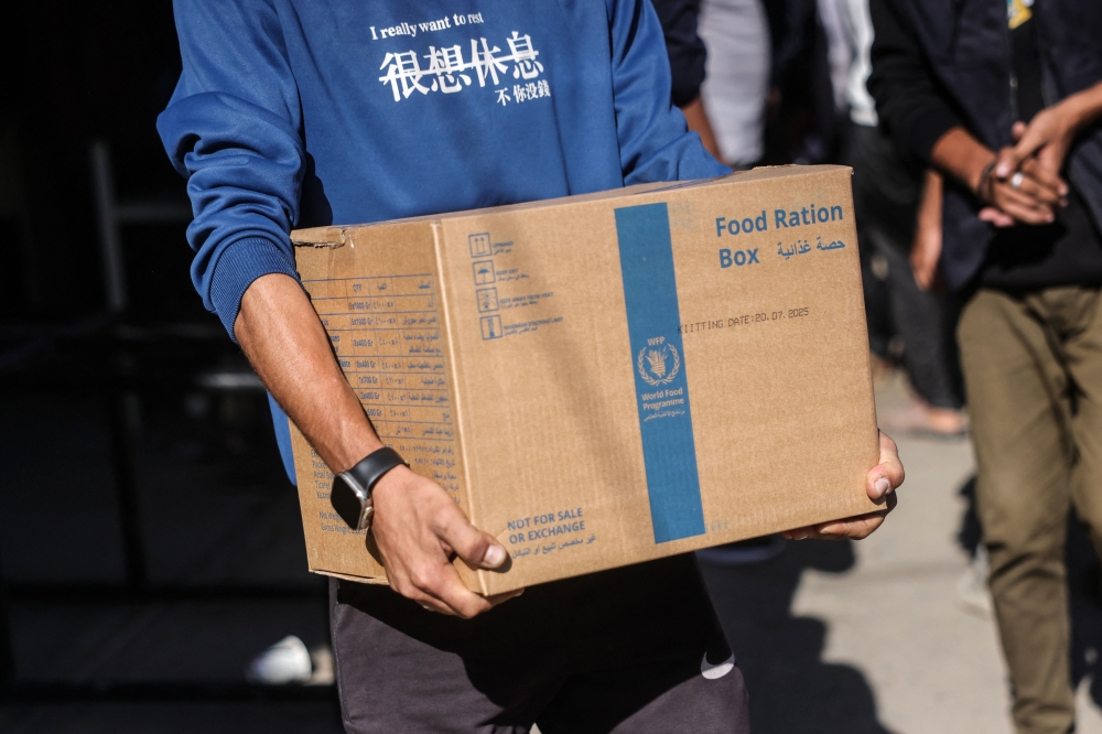A Palestinian man carries a food ration box provided by the World Food Programme (WFP), at a distribution centre in the village of Al-Zawayda, in the centre of the Gaza Strip on October 27, 2025. — AFP pic 
