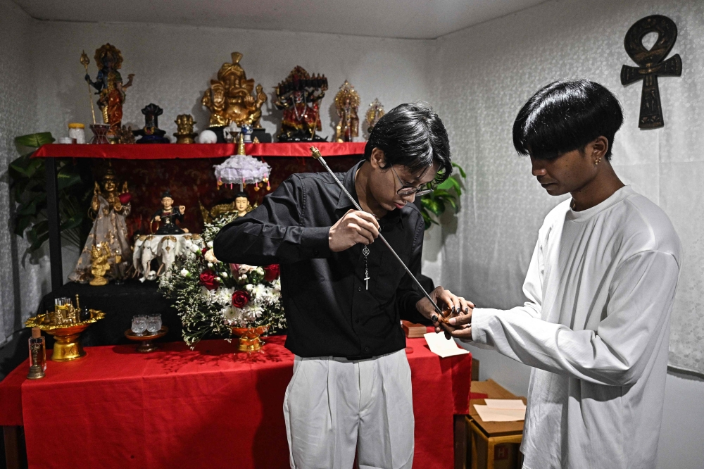 This photo taken on December 7, 2025 shows astrologer Linn Nhyo Taryar from Myanmar preparing to administer a sacred tattoo on a believer at his home in Bangkok. — AFP pic 