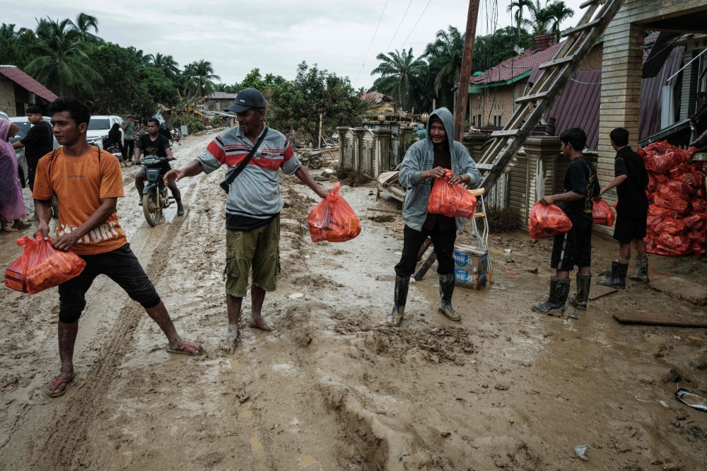 People unload aid supplies for distribution in Babo, Aceh Tamiang, Northern Sumatra, on December 15, 2025, following a flash flood. — Bernama pic