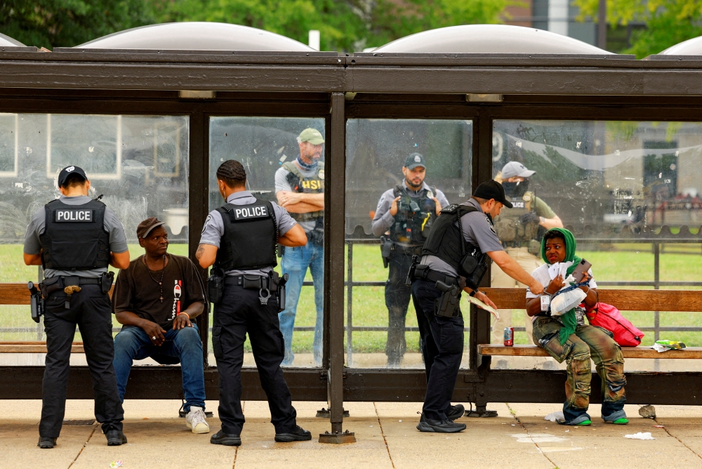 Police officers check individuals at the Anacostia bus station in Washington, D.C. August 20, 2025. — Reuters pic