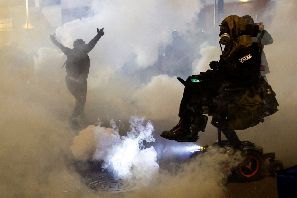 A person gestures amid tear gas as law enforcement officers advance to disperse demonstrators near U.S. Immigration and Customs Enforcement (ICE) headquarters in Portland, Oregon October 4, 2025. — Reuters pic