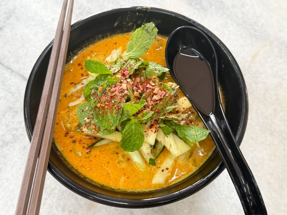 From Penang to PJ SS2, Granny Q's Lemak Laksa is a bowl of happiness with its fragrant, coconut rich broth freshened up with an assortment of mint leaves, torch ginger flower, pineapple and cucumber. — Picture by Lee Khang Yi