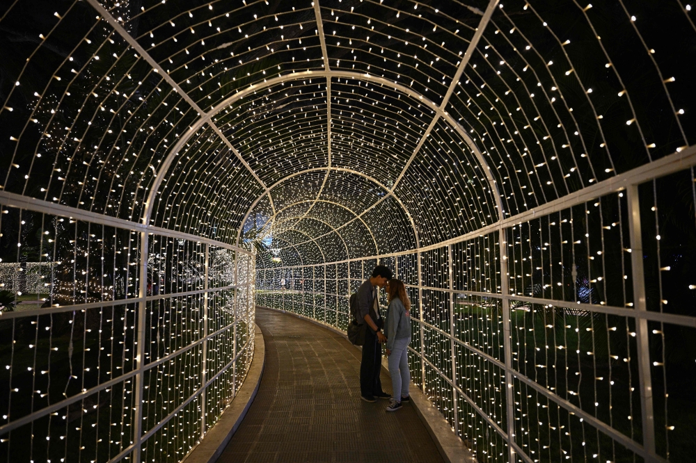 A couple stands inside a Christmas decoration at Los Proceres boulevard in Caracas December 19, 2025. — AFP pic