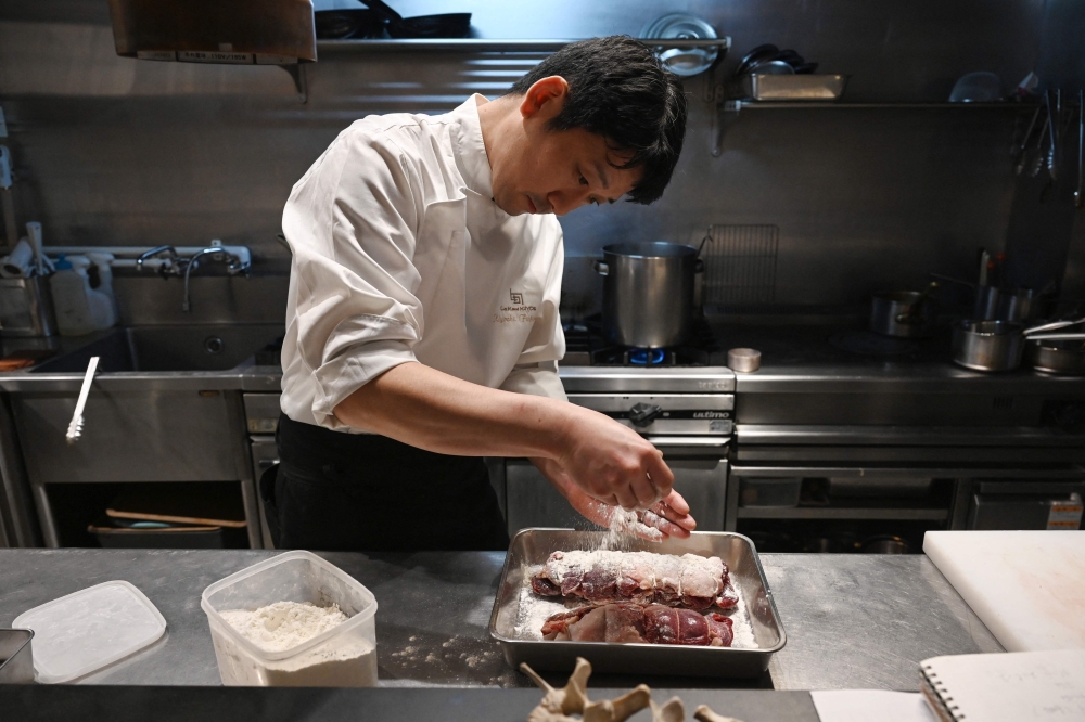 Chef Kiyoshi Fujimoto seasons bear meat as he prepares it for customers at his restaurant in Sapporo December 9, 2025. — AFP pic