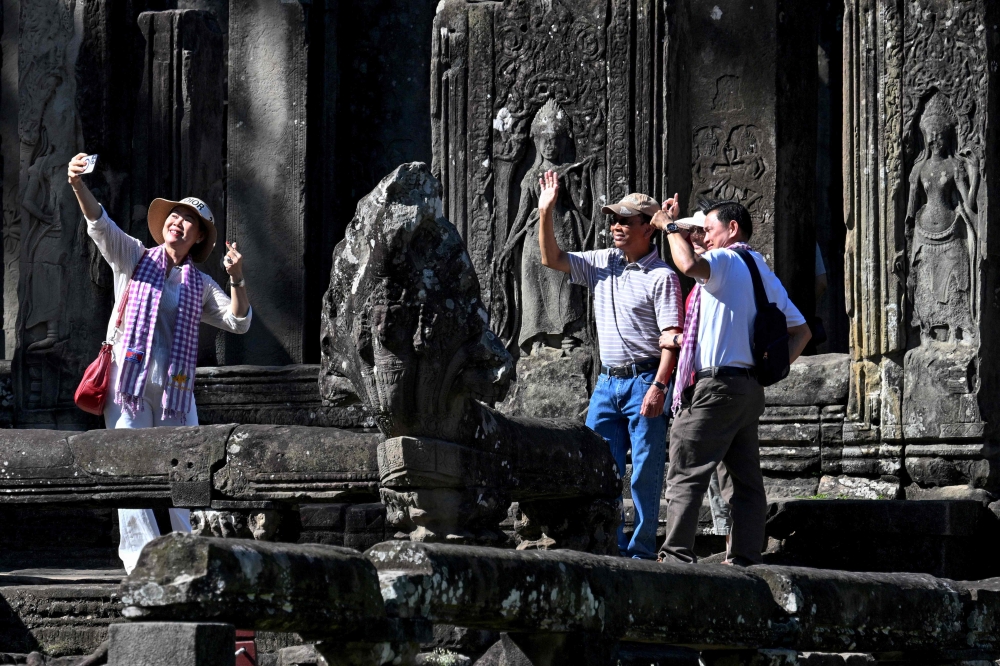 Tourists take selfies as they visit the Bayon temple in Siem Reap province December 18, 2025. — AFP pic