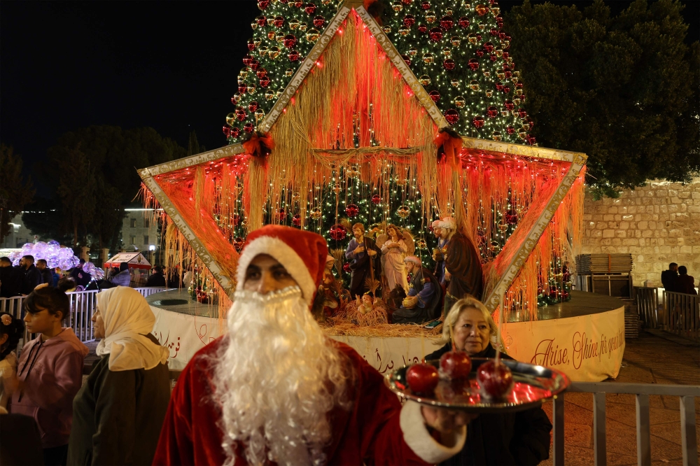 A man dressed as Santa Clause reacts at the Nativity Square with pilgrims and people before midnight mass at the Nativity Church in Bethlehem, in the Israeli-occupied West Bank, on December 24, 2025. — AFP pic