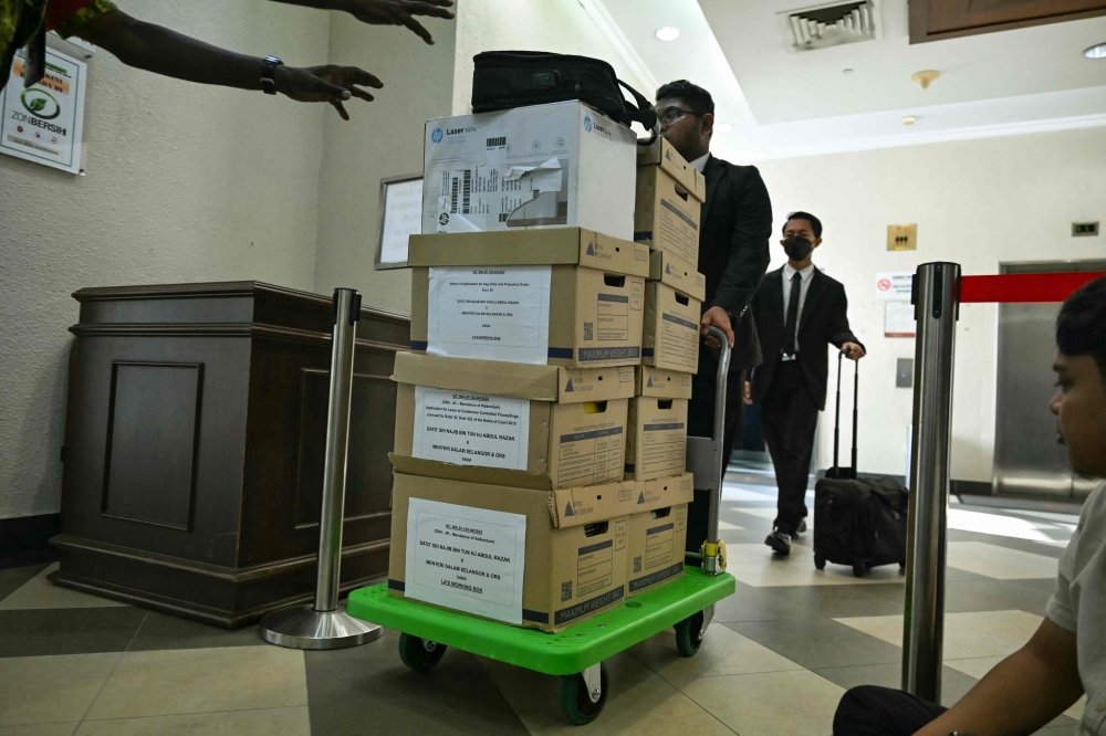 Lawyers wheel boxes of court files for jailed former Malaysian prime minister Najib Razak’s hearing December 22, 2025. — AFP pic