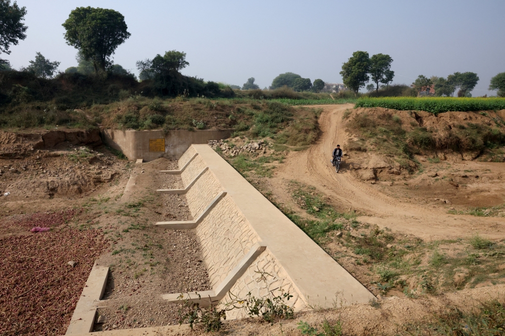 A man rides a motorcycle past a dry check dam built by Diageo in a village in Alwar, Rajasthan, November 20, 2025. — Reuters pic