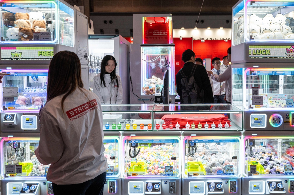 Staff members of Stand-by Amusement Company standing by claw crane game machines during the Amusement Expo 2025 in Tokyo November 14, 2025. — AFP pic